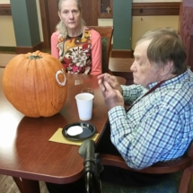 Pumpkin Painting-Shoreview Senior Livinng-senior man looking at his pumpkin